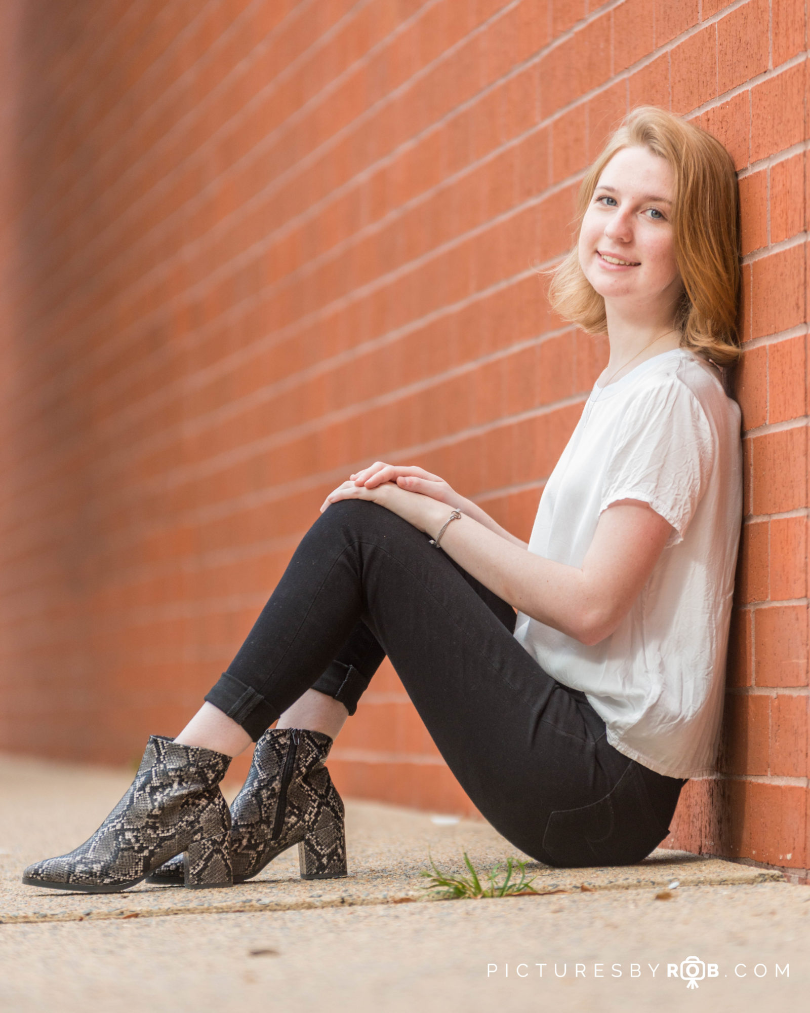 Dennis Senior Pics sitting against brick wall